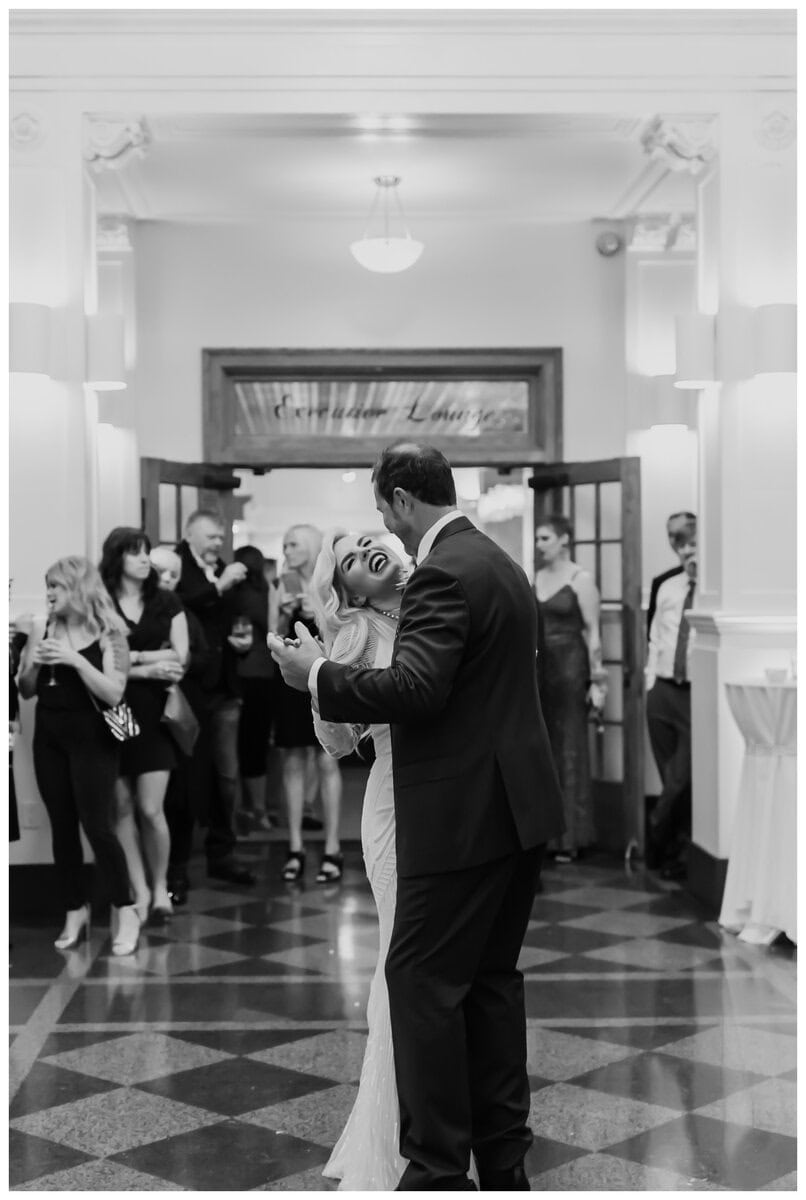 Bride and groom share a joyful first dance surrounded by guests at an elegant wedding venue. Perfect inspiration for couples looking for cool first dance songs. 