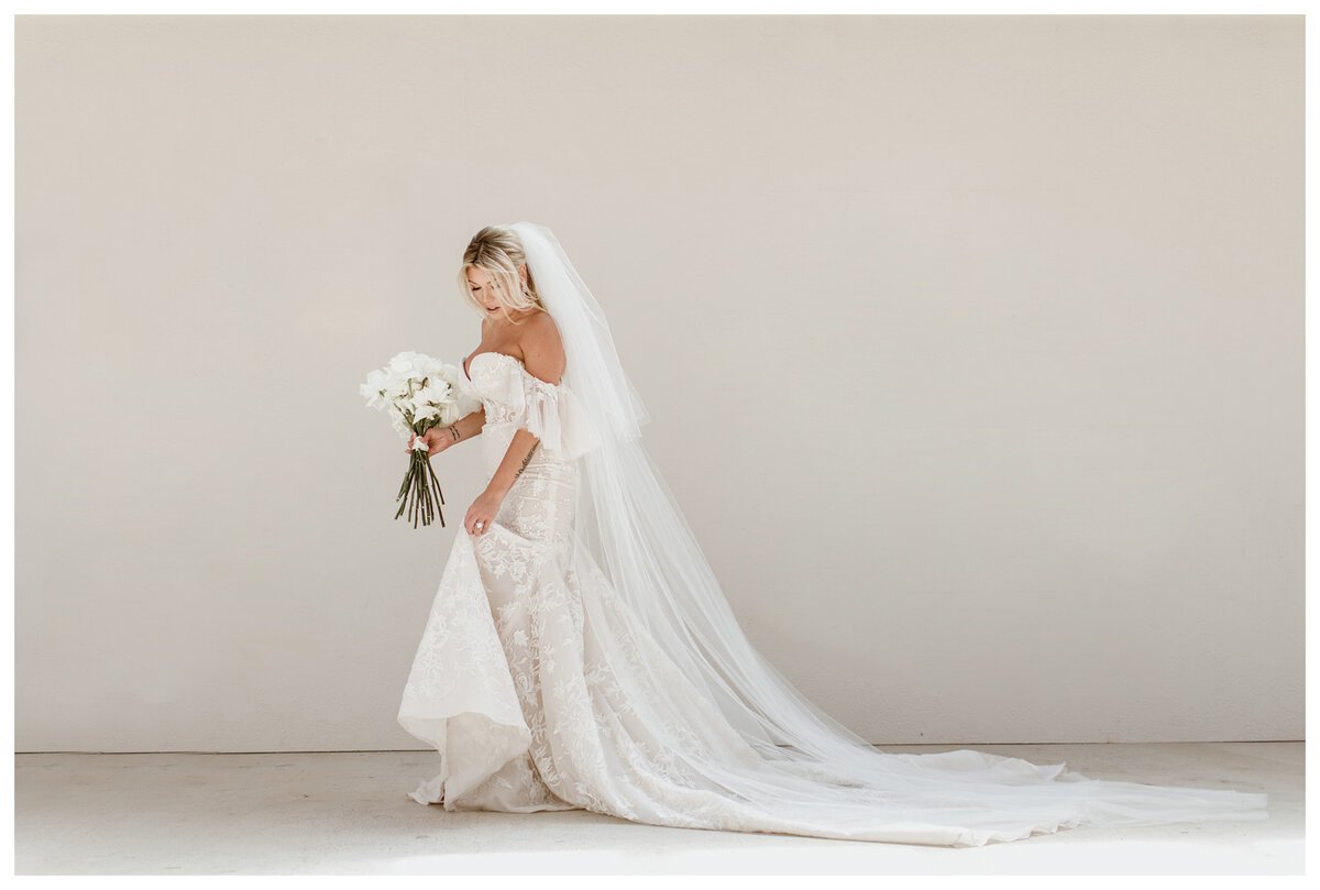 Bride at Lazy S Hacienda wedding venue, wearing a lace off-the-shoulder wedding gown with a long flowing veil. Elegant getting ready wedding photos capturing bridal beauty and anticipation.