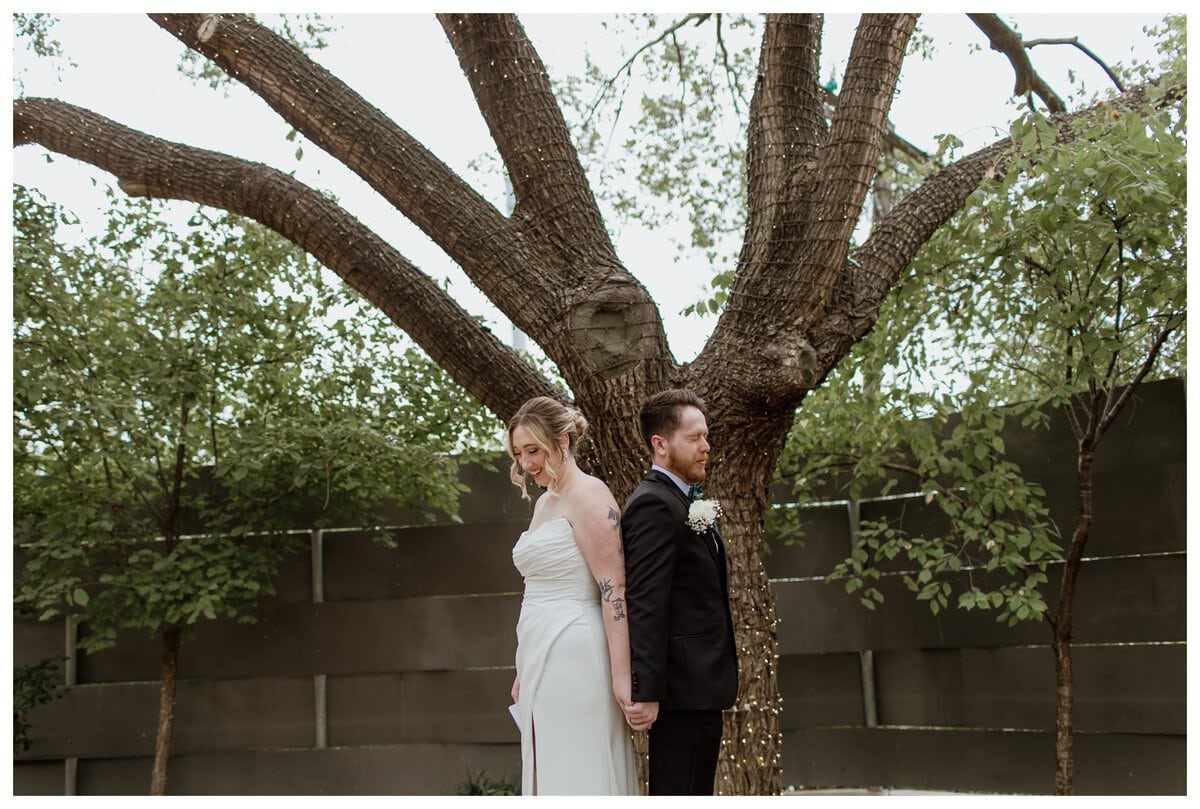 A heartfelt first touch moment at Artspace111 Fort Worth wedding, where the bride and groom stand back-to-back, holding hands and exchanging personal vows before their ceremony.