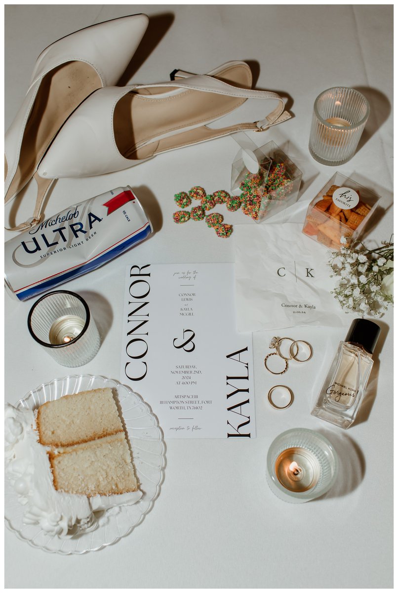 Late-night flat lay details at Artspace111 Fort Worth wedding venue featuring bridal shoes, wedding rings, invitation suite, candles, cake slices, and other personalized wedding details.