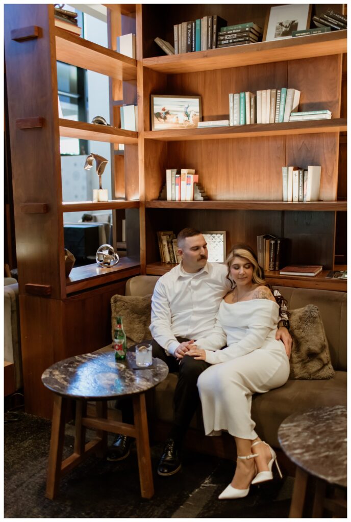 Engaged couple sitting cozy on a couch in a stylish downtown Fort Worth bar during their engagement photo session.