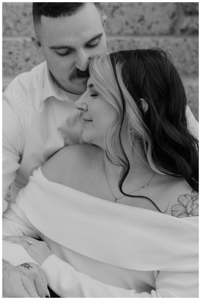 Engaged couple sitting on the grand stone steps of the Tarrant County Courthouse in downtown Fort Worth, sharing a romantic moment.