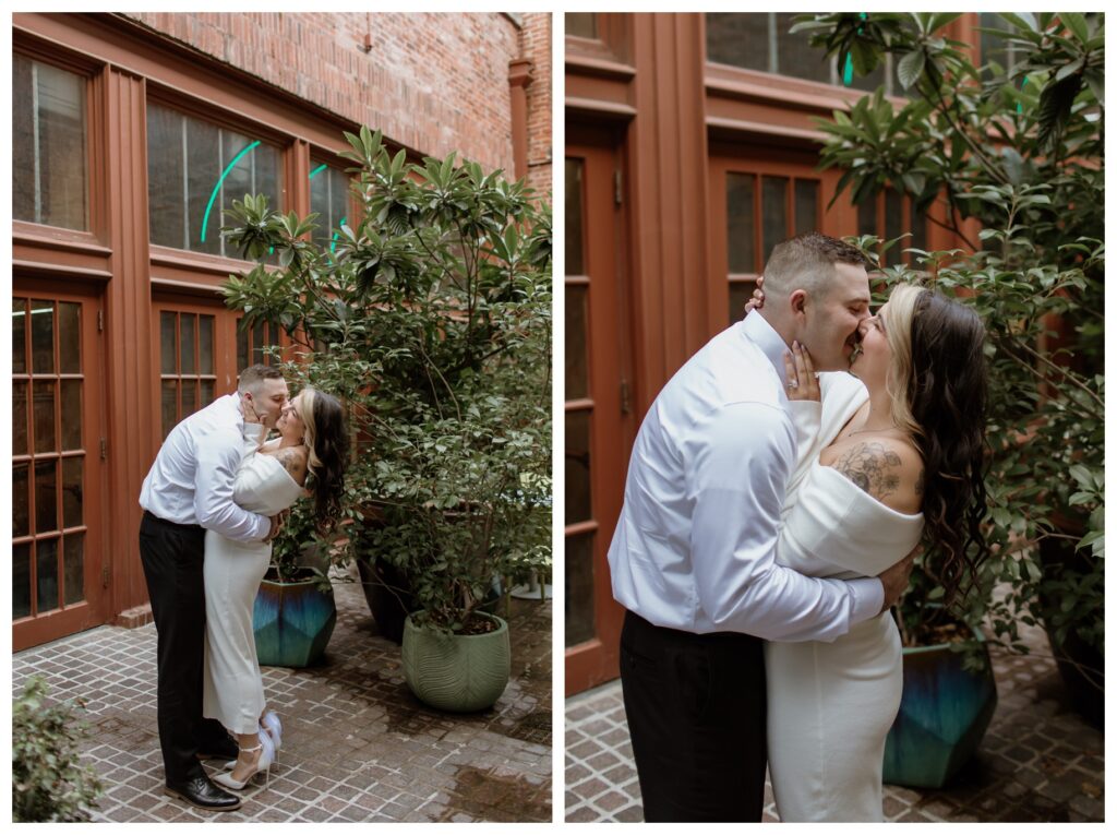 Romantic engagement photos in downtown Fort Worth's Sundance Square Alley, featuring a couple sharing a kiss among lush greenery and historic brick architecture.