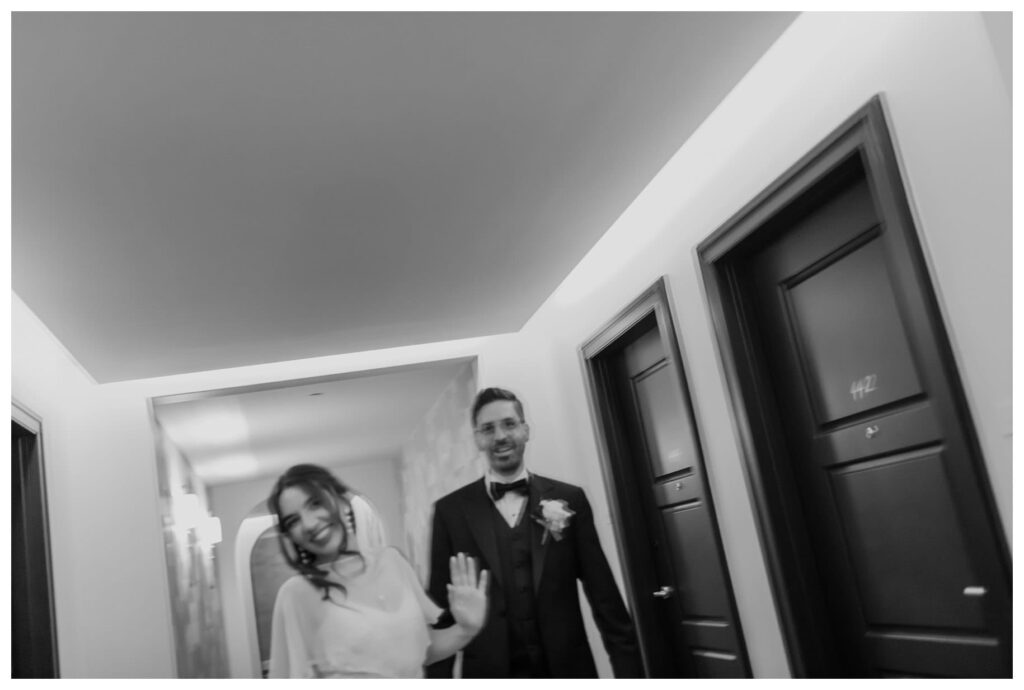 A bride and groom share a candid moment walking down the hotel hallway before their Bowie House wedding in Fort Worth.