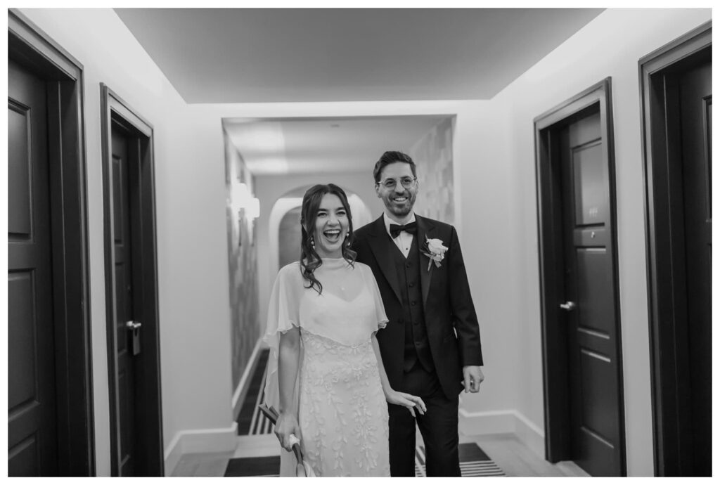 A bride and groom share a candid moment walking down the hotel hallway before their Bowie House wedding in Fort Worth.